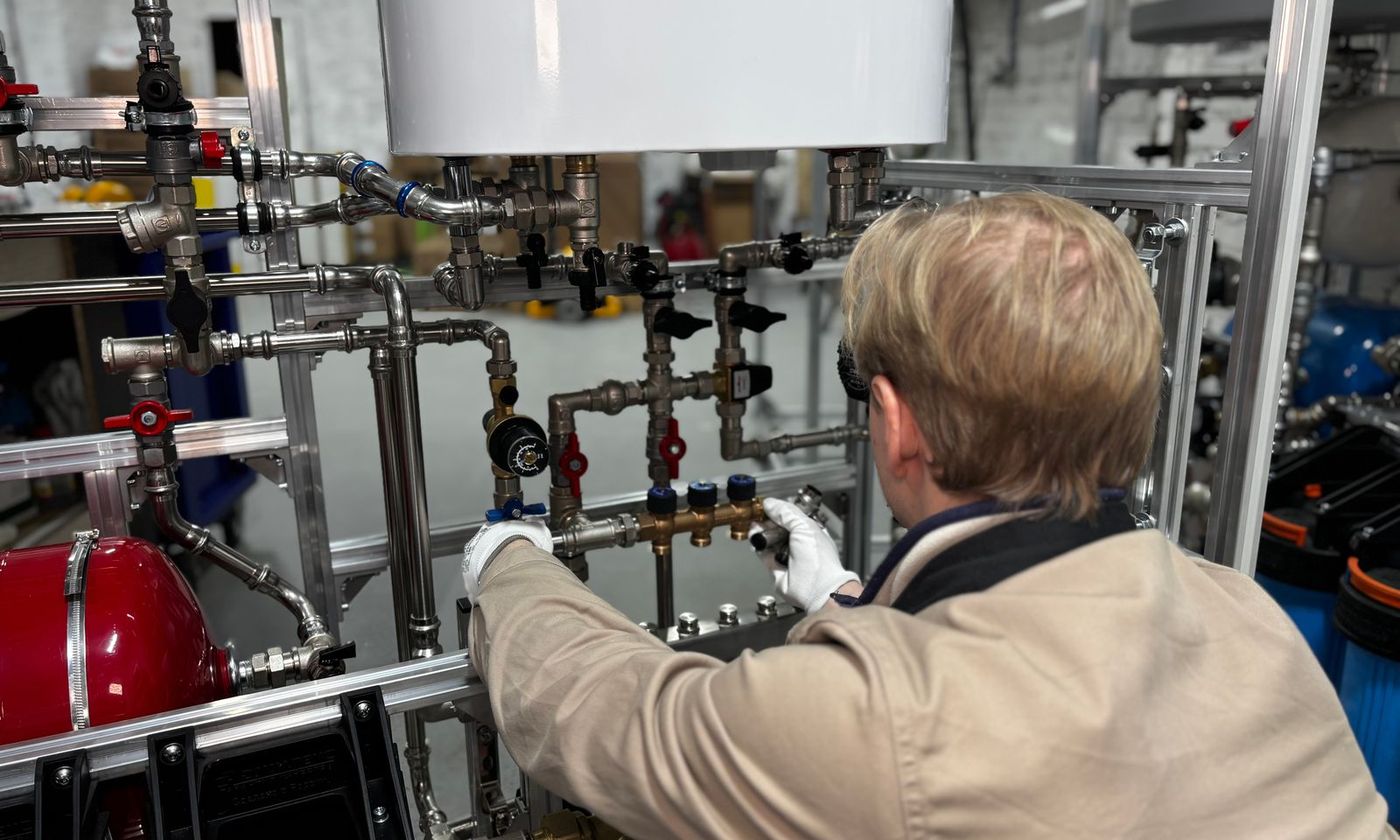 Technician connecting valves and piping beneath a newly installed water heater tank